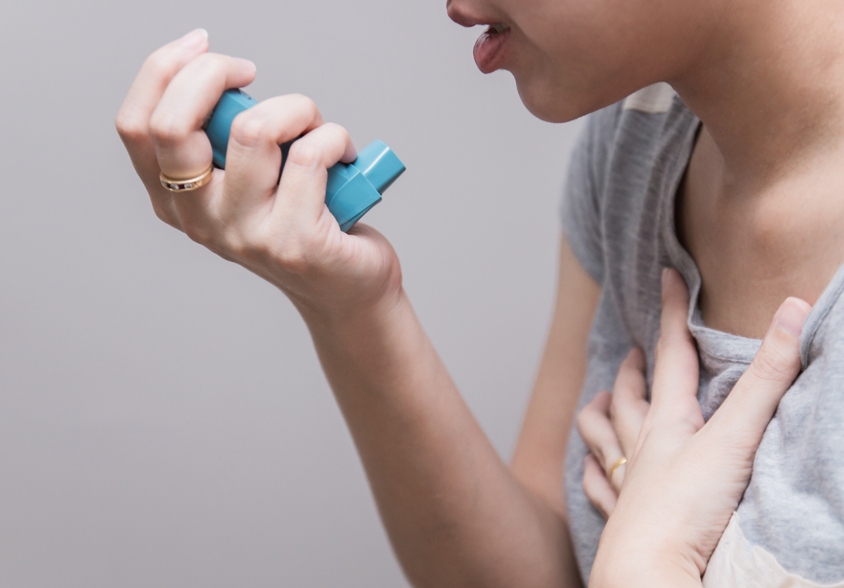 Woman using inhaler for asthma symptoms